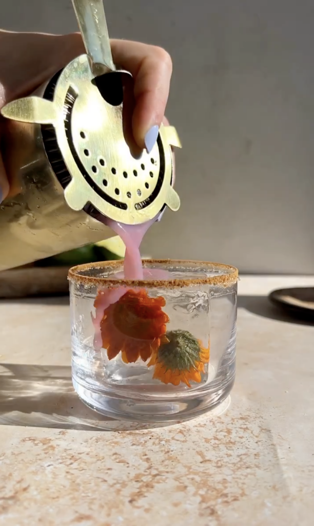 pouring hibiscus margarita sour over ice