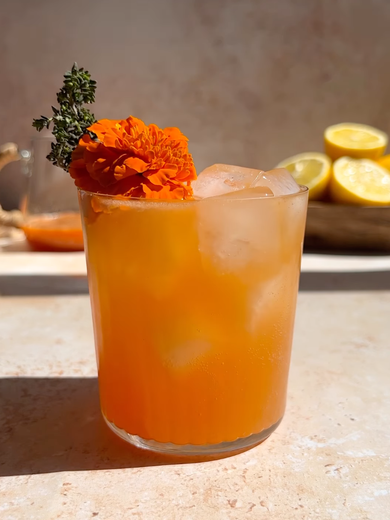 carrot bourbon spritzer with a marigold edible flower garnish