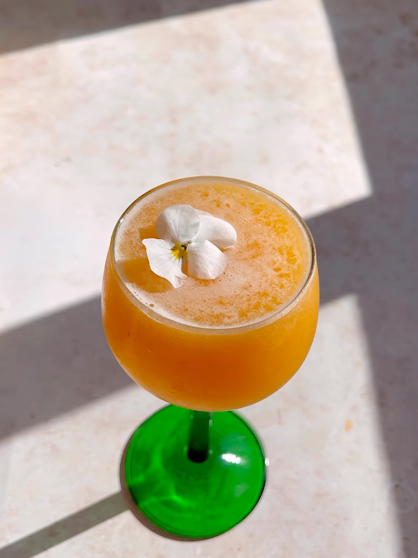 a single white edible flower on a cocktail